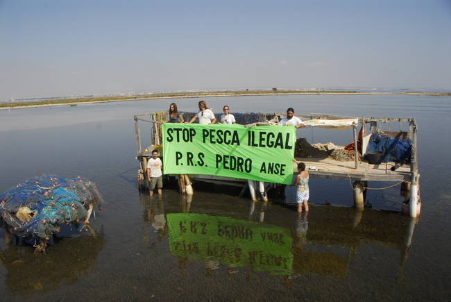 Voluntarios de ANSE protestan en agosto de 2014 sobre unas plataformas, actualmente retiradas, donde se almacenaban redes para pesca ilegal, en el Parque Regional Salinas y Arenales de San Pedro del Pinatar (Murcia). Foto: Pedro García.

