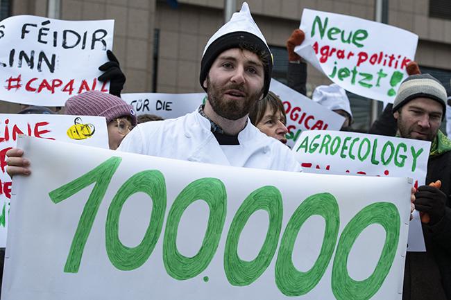Un activista sujeta en Bruselas una pancarta que recuerda el logro de cien mil firmas de ciudadanos europeos en favor de una PAC con más peso ambiental (foto: GFGF).