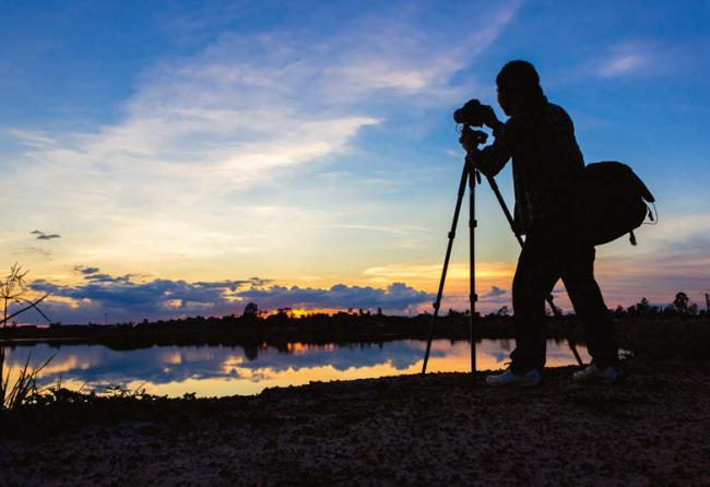 Un fotógrafo de la naturaleza practica su afición junto a un humedal (foto: sabzaa / 123rf).