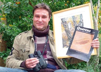 Isaac Vega en el jardín de su casa con un ejemplar del número 41 de Quercus (julio de 1989), donde publicó su primera colaboración, y una acuarela que representa a un pico menor (Dendrocopos minor), obra del ilustrador Antonio Ojea.